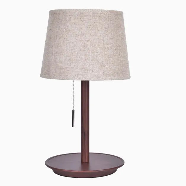 Walnut-colour solid wood desk lamp with a white fabric shade on a wooden table.