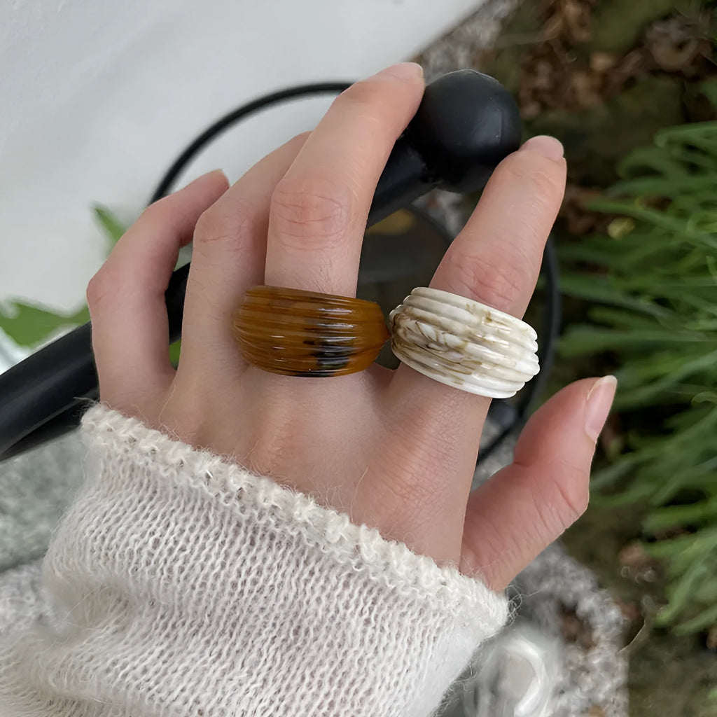 Geometric irregular resin wide ring in brown and white colours on a plain background.