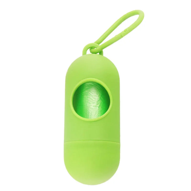Compact black dog poop bag holder with Velcro strap and metal side hook, shown next to a roll of waste bags.