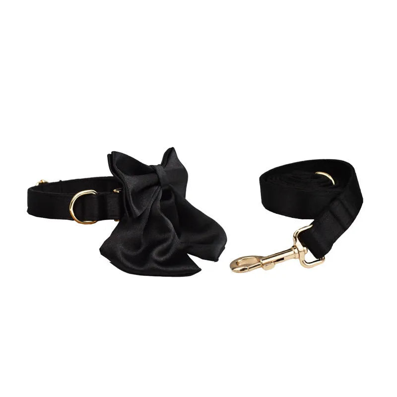 A soft cloth dog collar, leash, bow, and matching chest strap set laid out flat, showing coordinated colours.