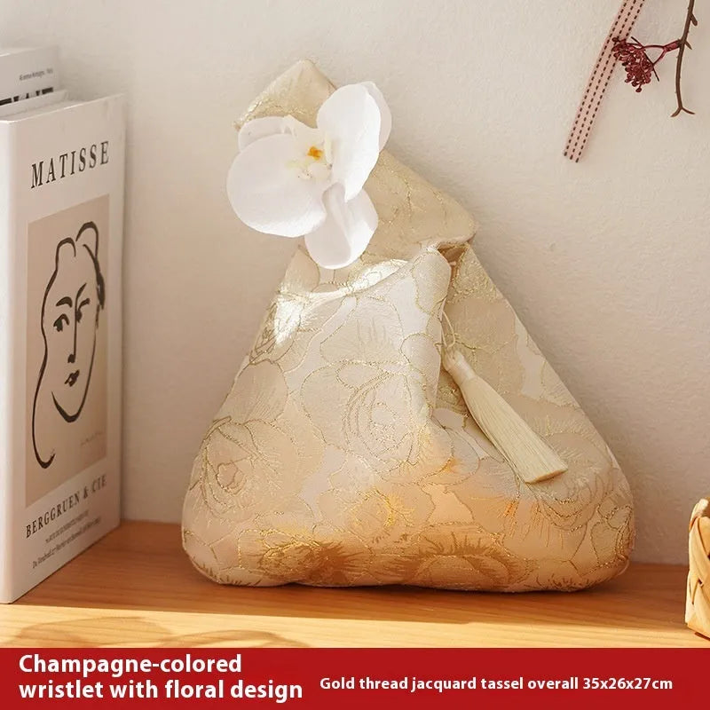 Chinese style gold silk jacquard hand-held cloth gift bag with flower accent in champagne colour on white background