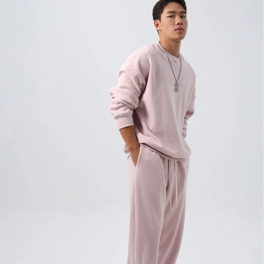 Man wearing a loose black polar fleece sports suit with a crew neck coat and trousers.