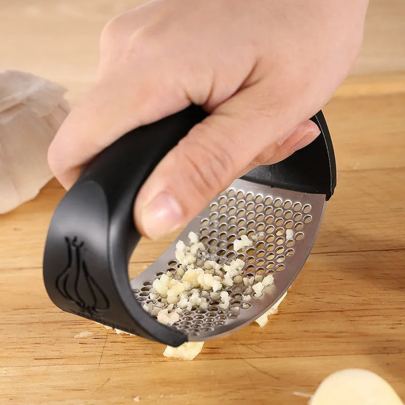 Stainless steel garlic press in green, showing compact 11cm design for crushing garlic.