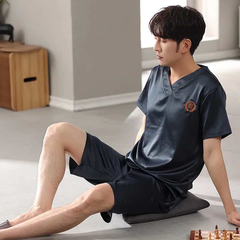 Man wearing a loose light blue short-sleeve pajama shirt and matching shorts, labelled as ice silk sleepwear.