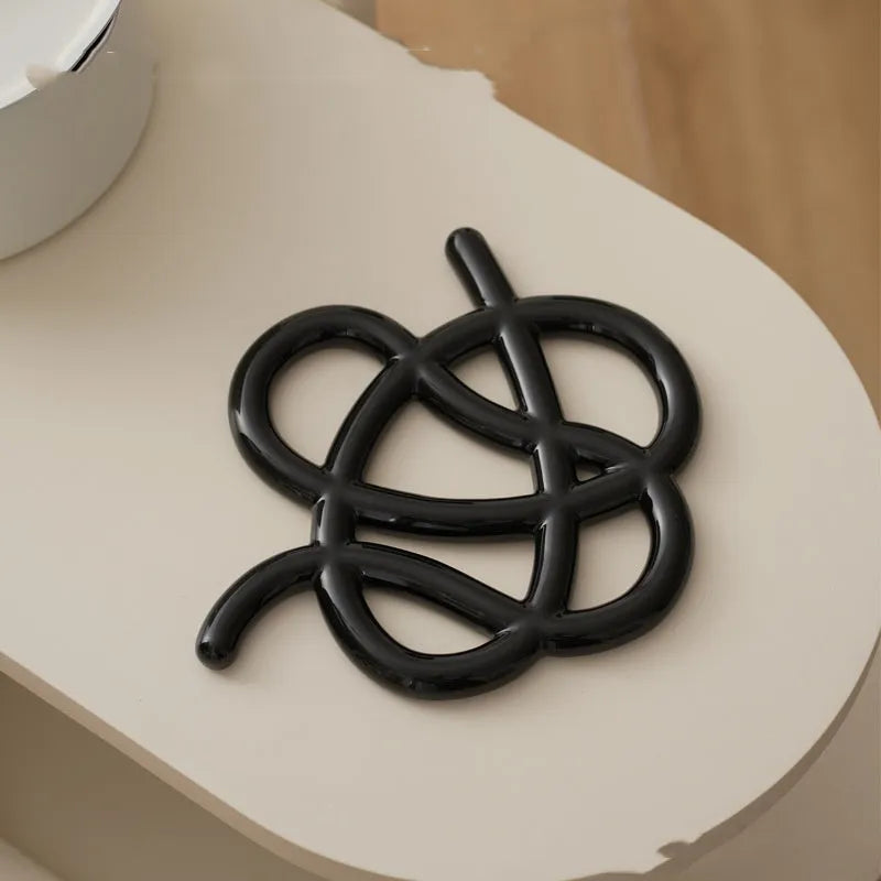 Ceramic heat proof mat with irregular shape on dining table, bright black solid colour