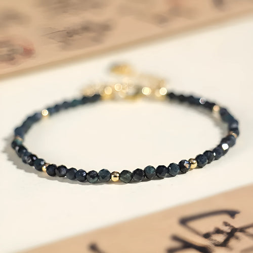 Close-up of a women's blue tourmaline gemstone beaded bracelet with 3mm beads and spacer design.