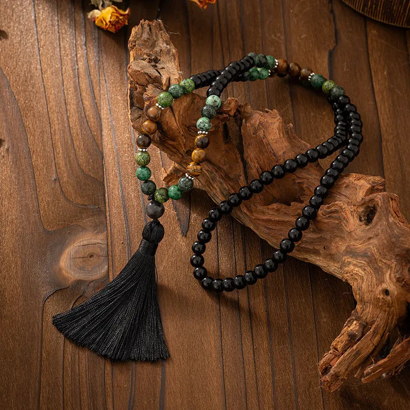 Long natural stone beaded sweater chain necklace and matching bracelet in bohemian style on a grey background.