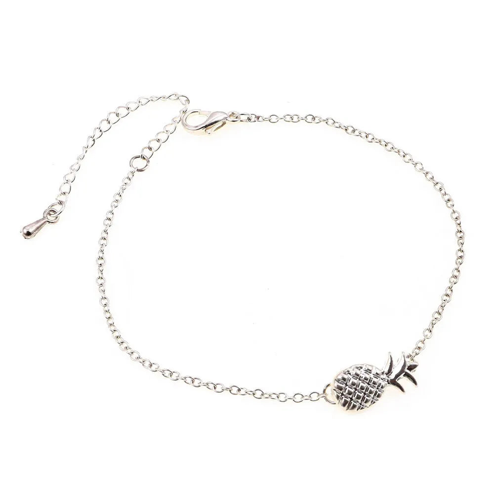 Close-up of a gold-coloured alloy bracelet with a pineapple charm on a simple chain.