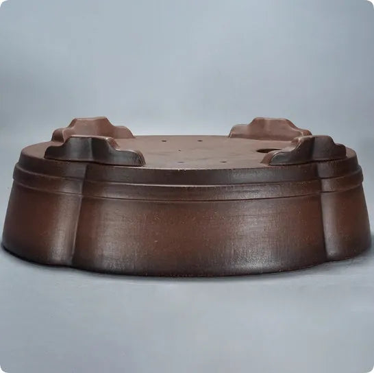 A large, classical-style purple clay flower pot on a wooden floor.