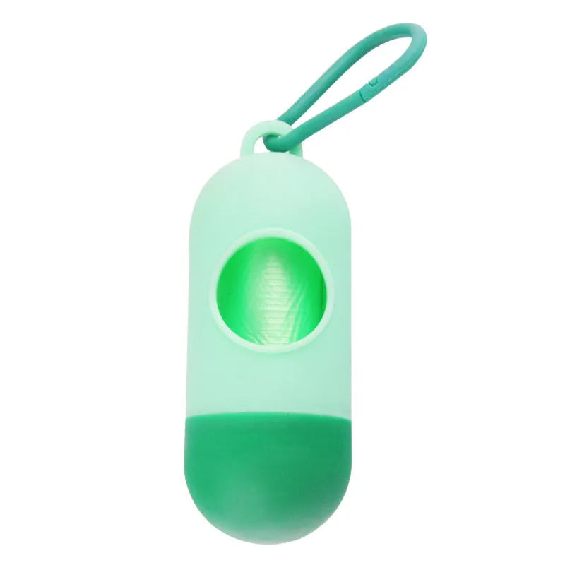 Compact black dog poop bag holder with Velcro strap and metal side hook, shown next to a roll of waste bags.