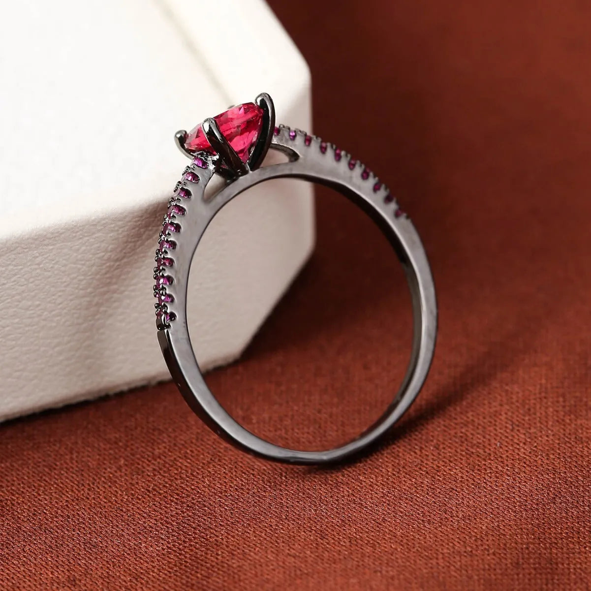 Hexagon geometric zircon ring on a finger, showing electroplated gold rose red colour and copper band.