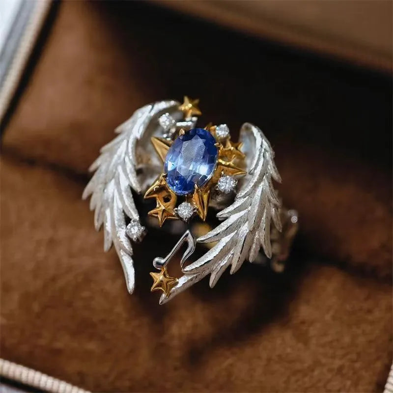 Gold-tone geometric angel wings alloy ring with adjustable opening on a finger.