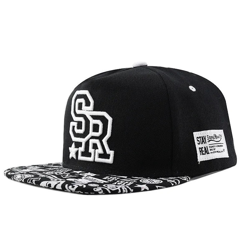 Cotton baseball cap with embroidered letters in black or white, showing adjustable strap.