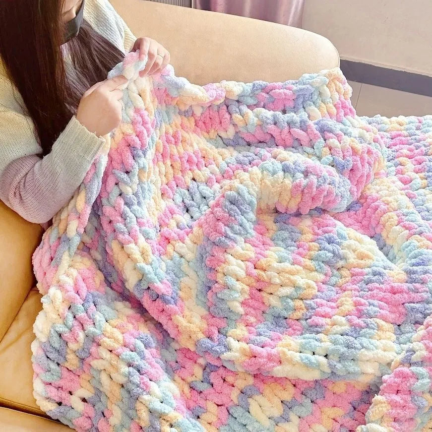 Coarse yarn chenille knitted blanket with braided gravity trim in a modern colour on a bed.