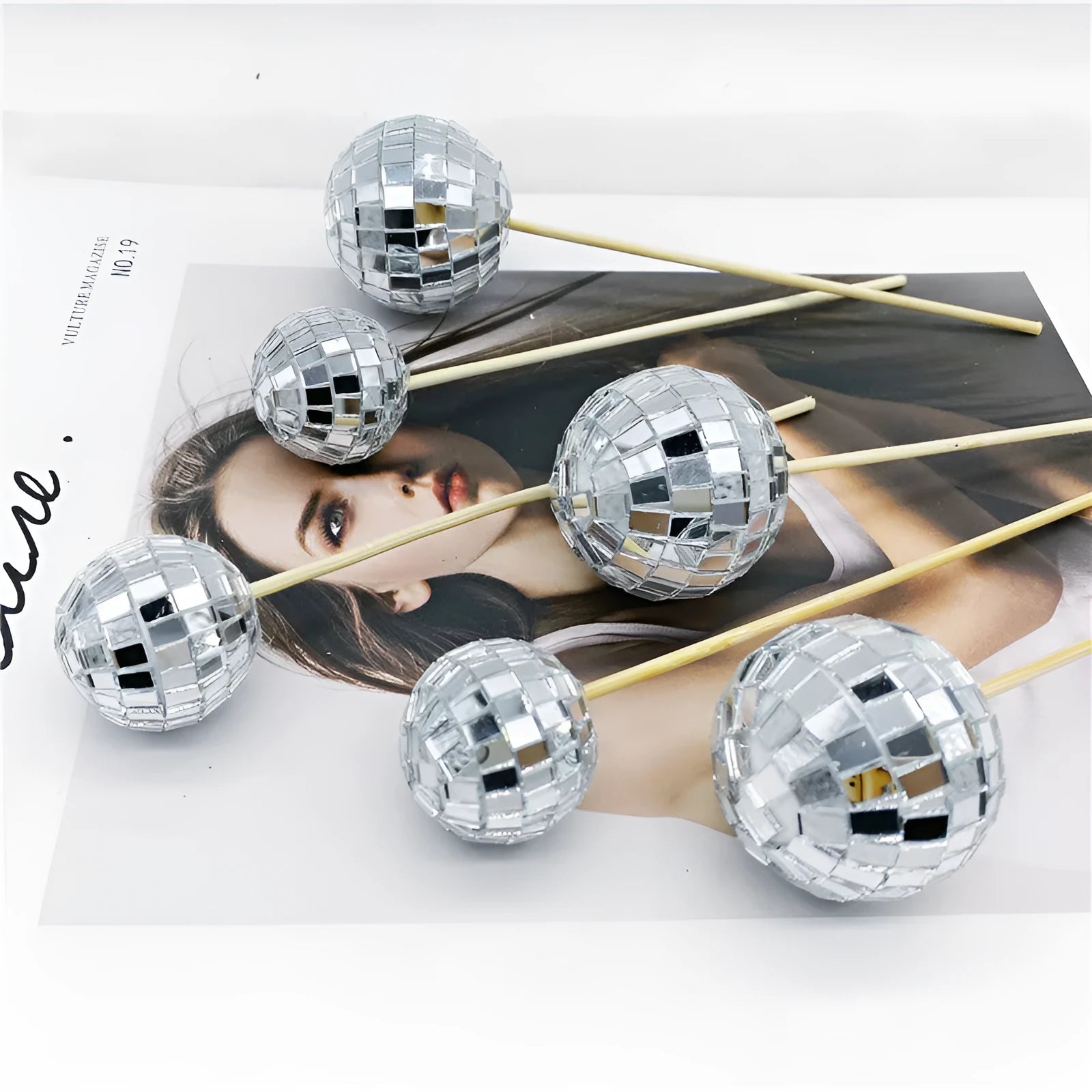 Glass mirror ball cake decoration on a wooden stick, showing reflective surface.