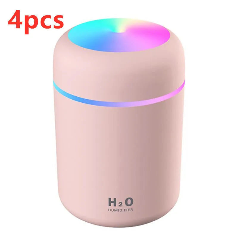 Pink USB desktop humidifier with coloured lights and water tank on a wooden desk