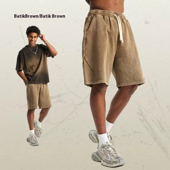 Men's loose black batik washed cotton shorts with patch craft design on a neutral background.