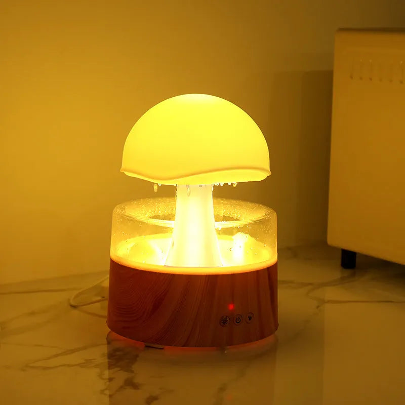 White cloud-shaped humidifier and aroma diffuser with LED lights and mist output on a wooden table.