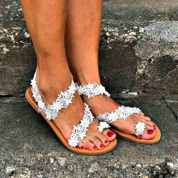 White women's flat sandals with rhinestone flower decoration on patent leather upper