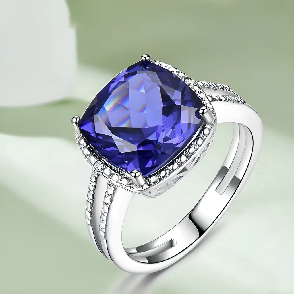 Women's sterling silver ring with oval blue Tanzanite gemstone on a finger.