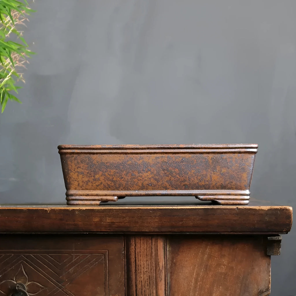 Rectangular purple sand bonsai pot with firewood burning texture on a floor.