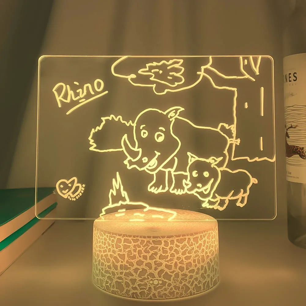 Black 3D acrylic message board night light on desk with remote control and stylus.