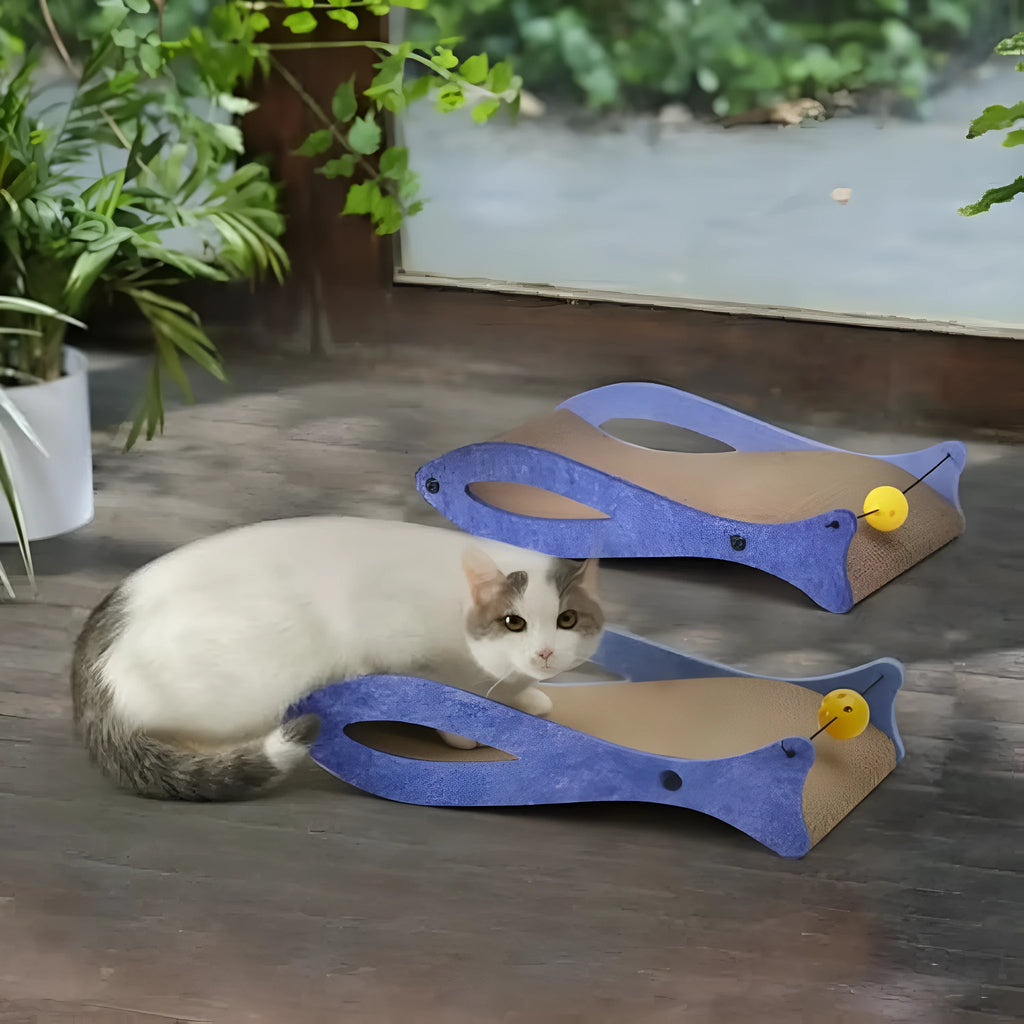Blue fish-shaped cardboard cat scratcher lounge with dangling ball toys on an elastic cord.
