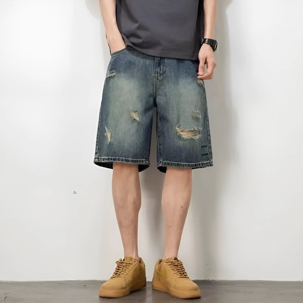Blue denim men's shorts with distressed holes and straight cut design on mannequin