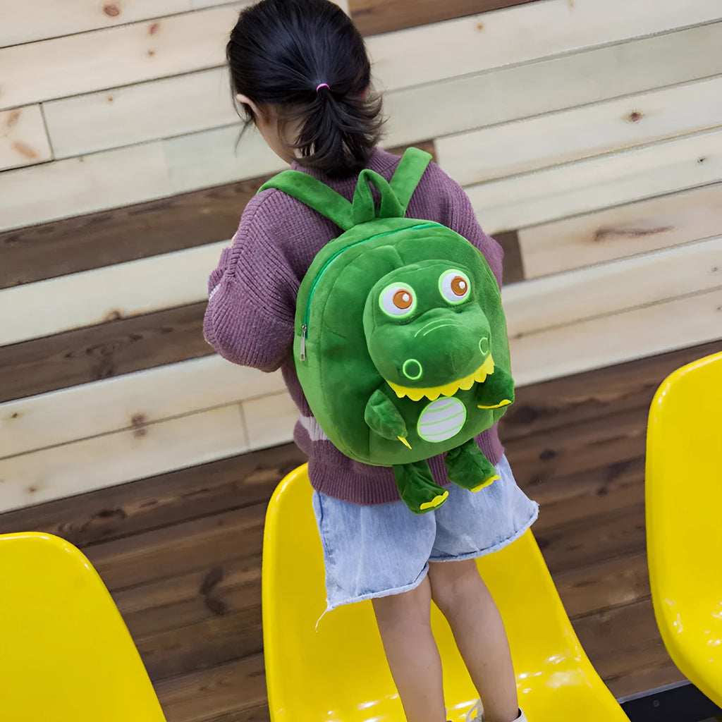 Blue baby dinosaur plush backpack with embroidered detail and a soft handle.