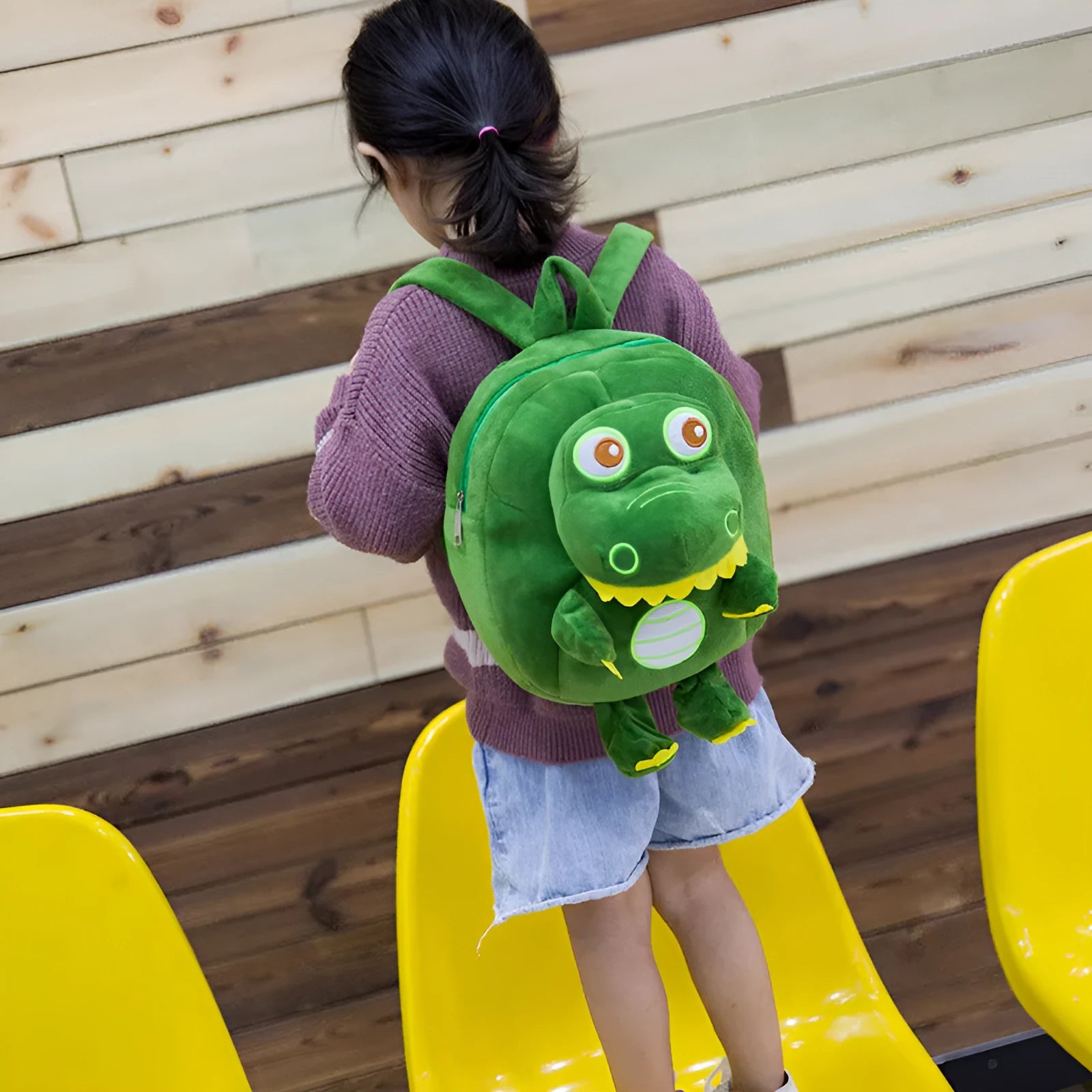 Blue baby dinosaur plush backpack with embroidered detail and a soft handle.