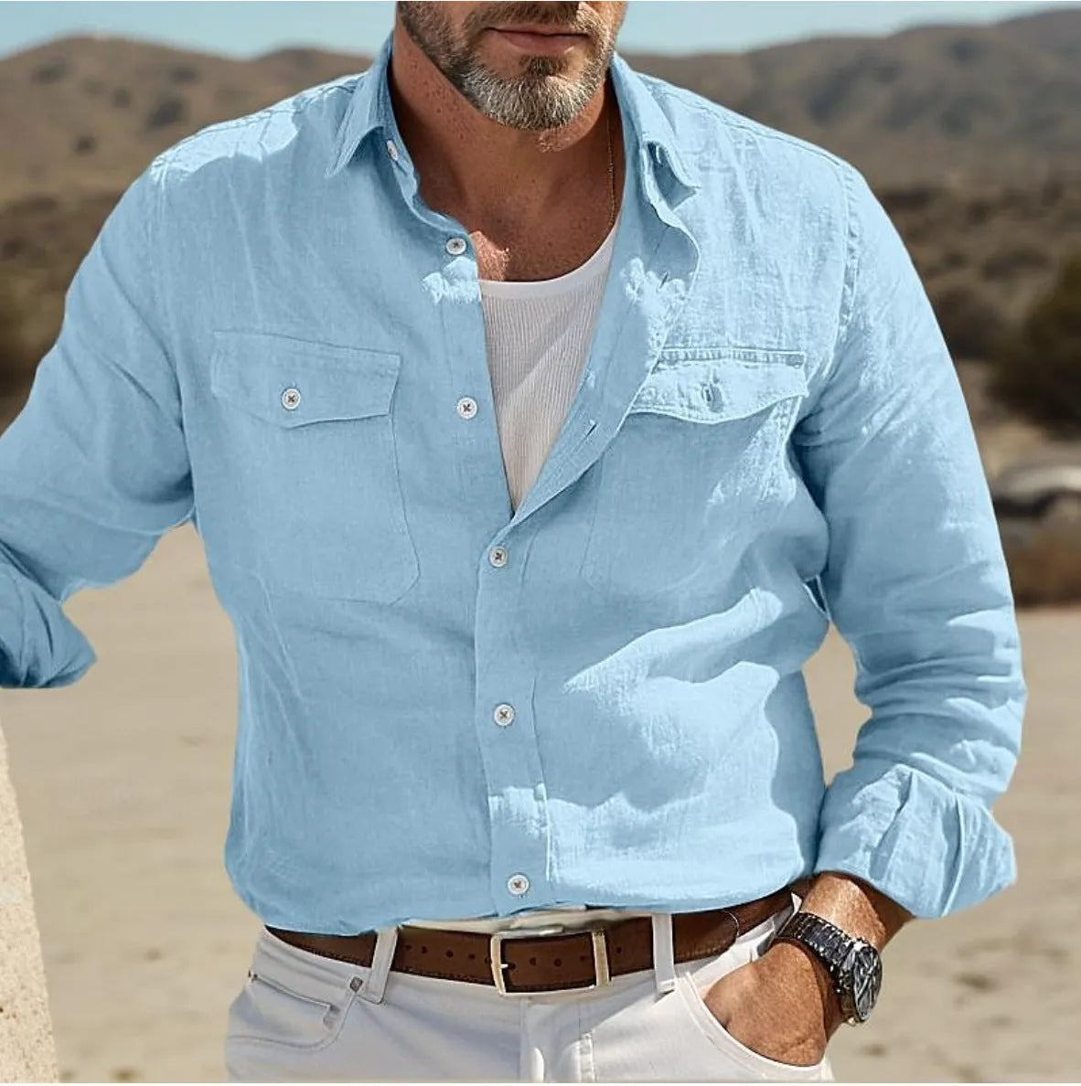 A man wearing a loose-fit, long-sleeved shirt in a solid colour, made from cotton and linen fabric.