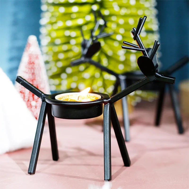Black iron Christmas candlestick holder with decorative elk design on a table.