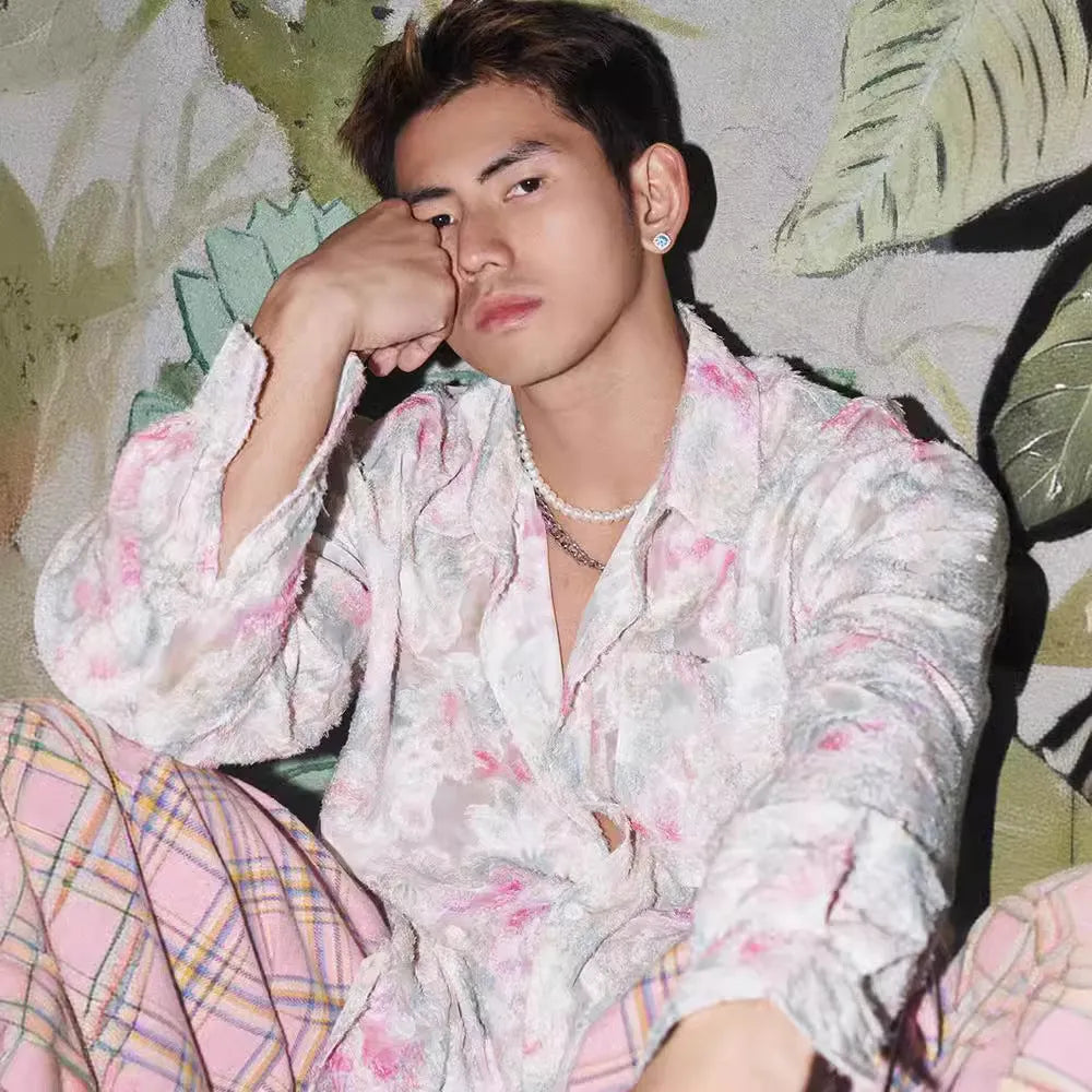 Man wearing a blue loose-fit long sleeve shirt with an embossed three-dimensional floral pattern.