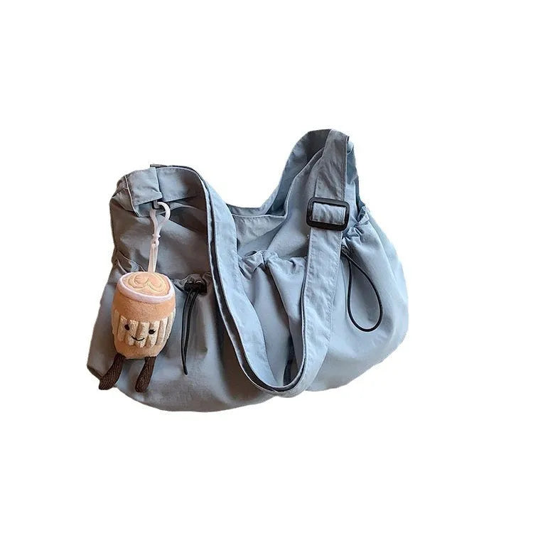 Ultra-light pleated green crossbody cloth bag lying flat, showing its split pocket and foldable design.