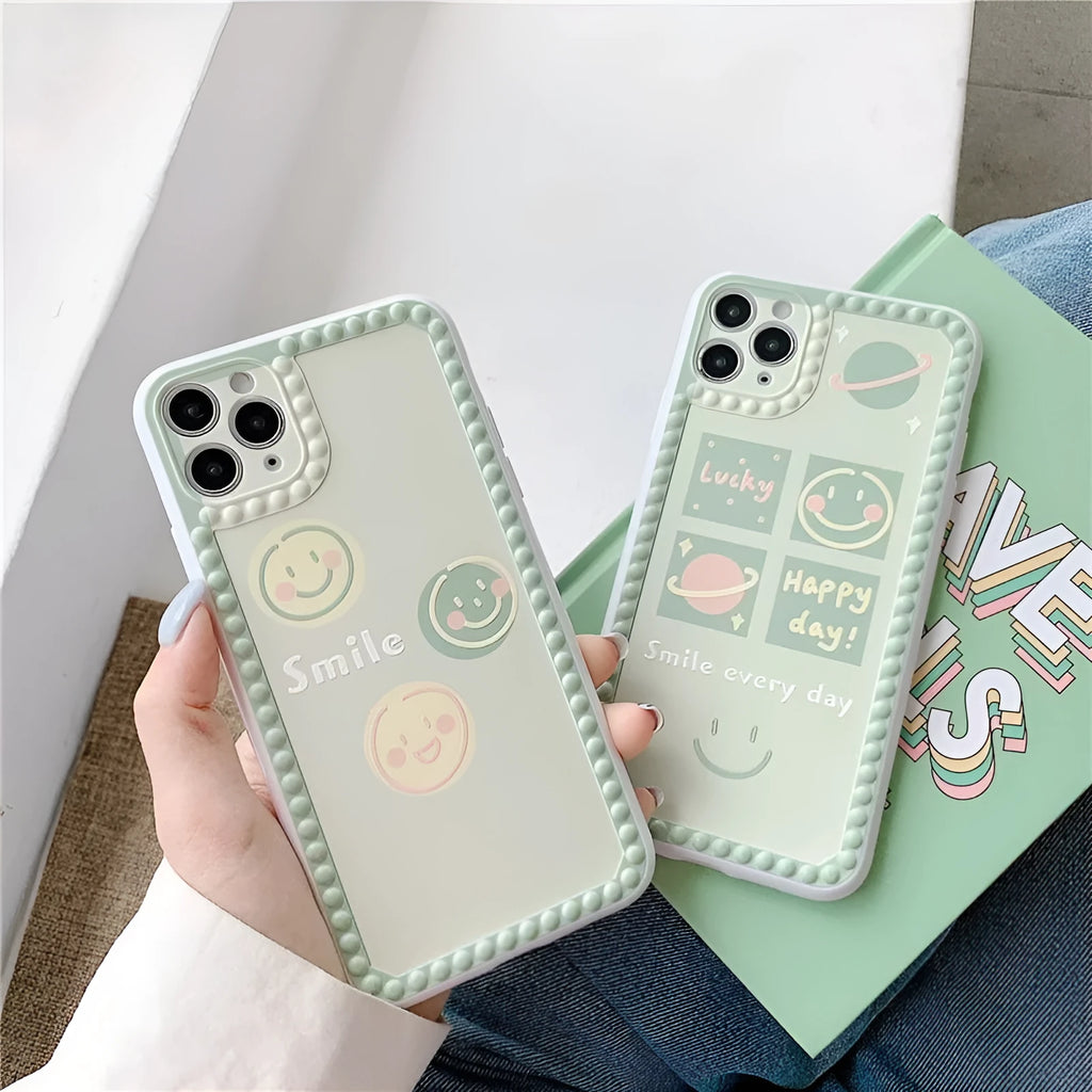 Green TPU iPhone case with geometric smiley face and polka dot frame design on a table.