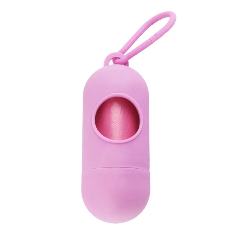 Compact black dog poop bag holder with Velcro strap and metal side hook, shown next to a roll of waste bags.