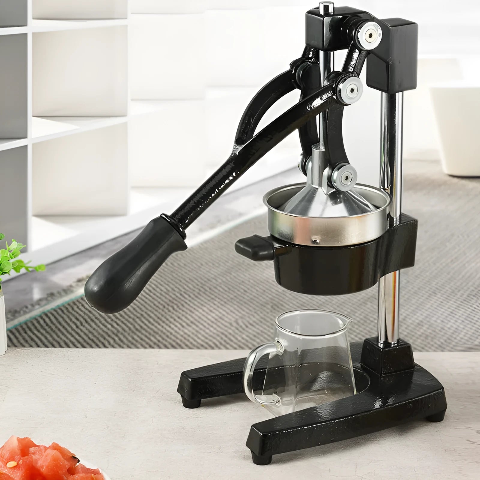 Black cast iron manual juicer with stainless steel strainer on kitchen counter