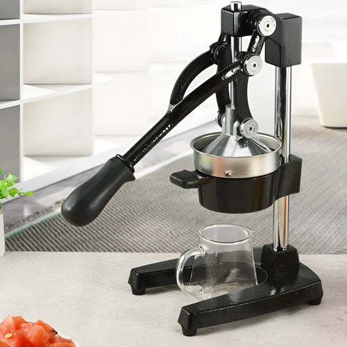 Black cast iron manual juicer with stainless steel strainer on kitchen counter