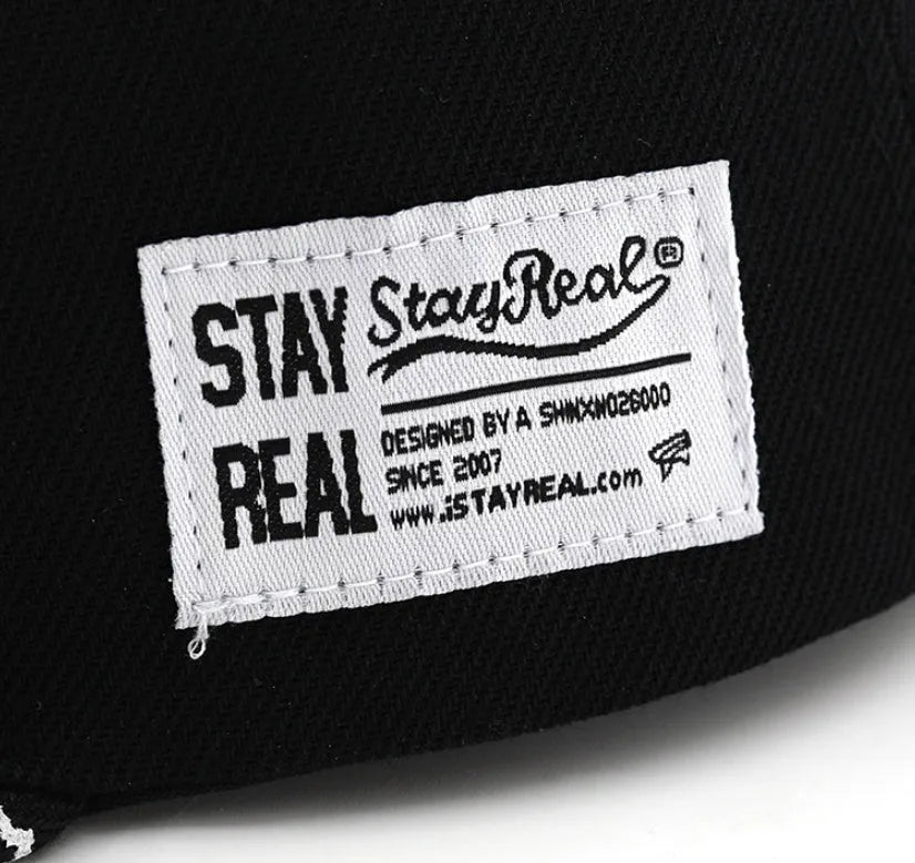 Cotton baseball cap with embroidered letters in black or white, showing adjustable strap.