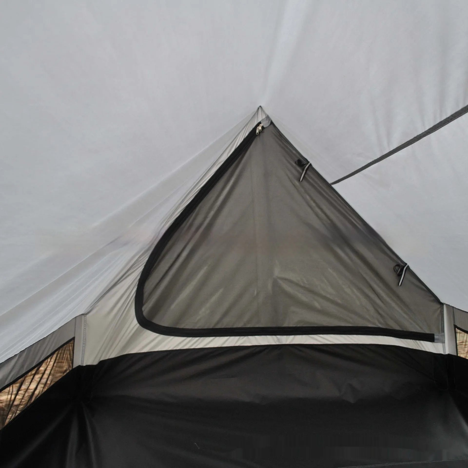 Brown A-line cabin tent pitched with hiking poles as structural support showing spacious interior for 2-3 people