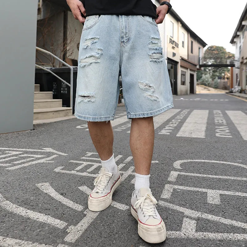 Light blue ripped denim shorts with distressed details, loose straight leg cut on a neutral background.
