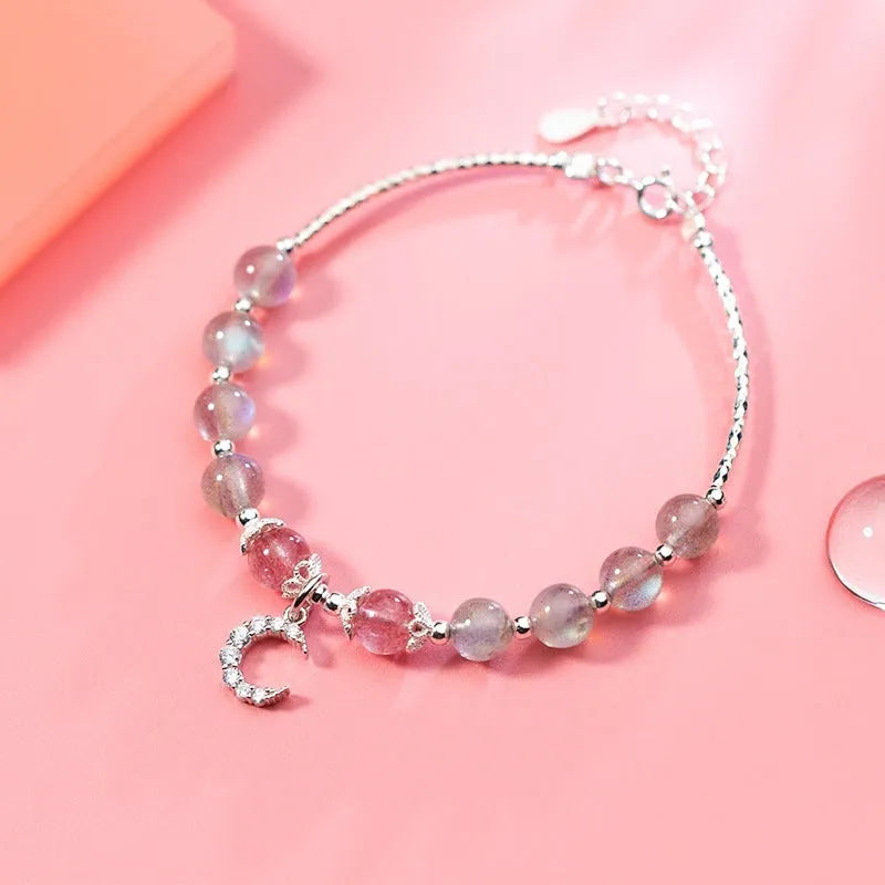 Natural moonstone bracelet with silver crescent moon charm on an adjustable chain.