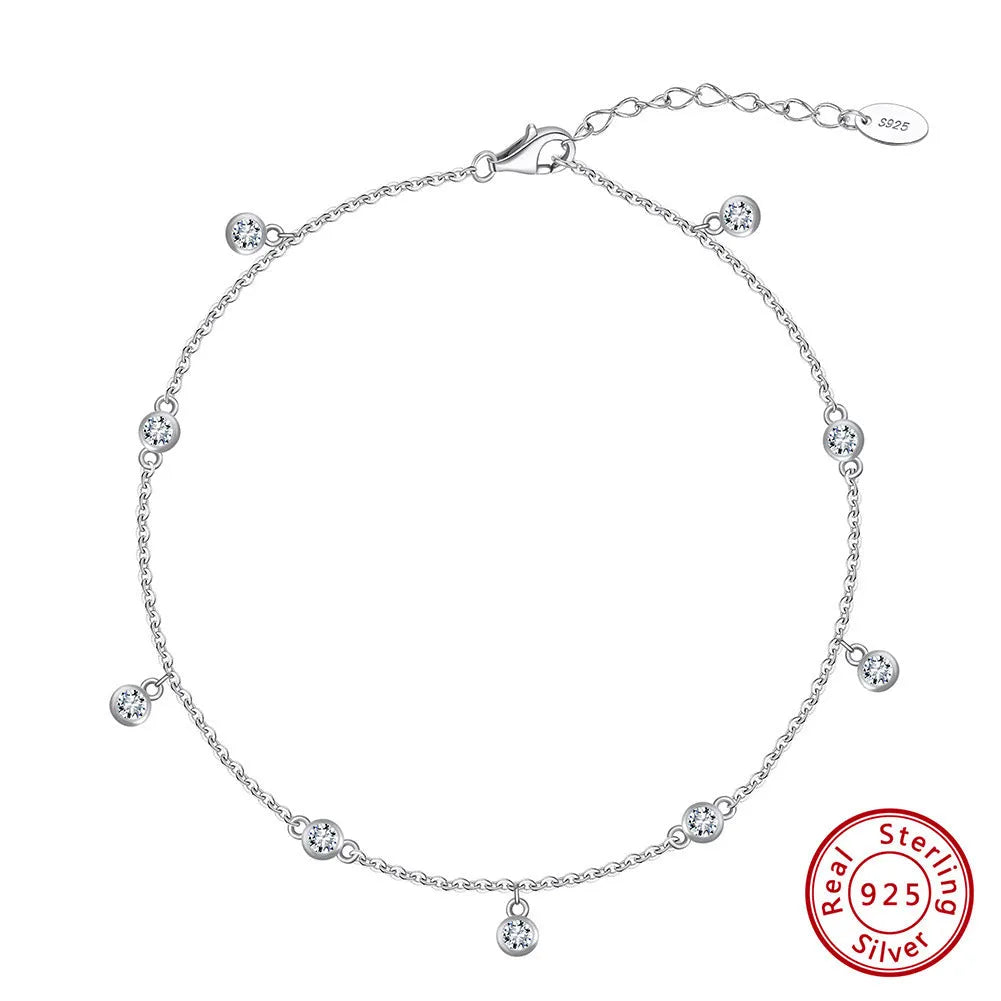 Close-up of a women's silver anklet with a small geometric zirconium pendant on a fine, adjustable chain.