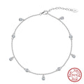 Close-up of a women's silver anklet with a small geometric zirconium pendant on a fine, adjustable chain.