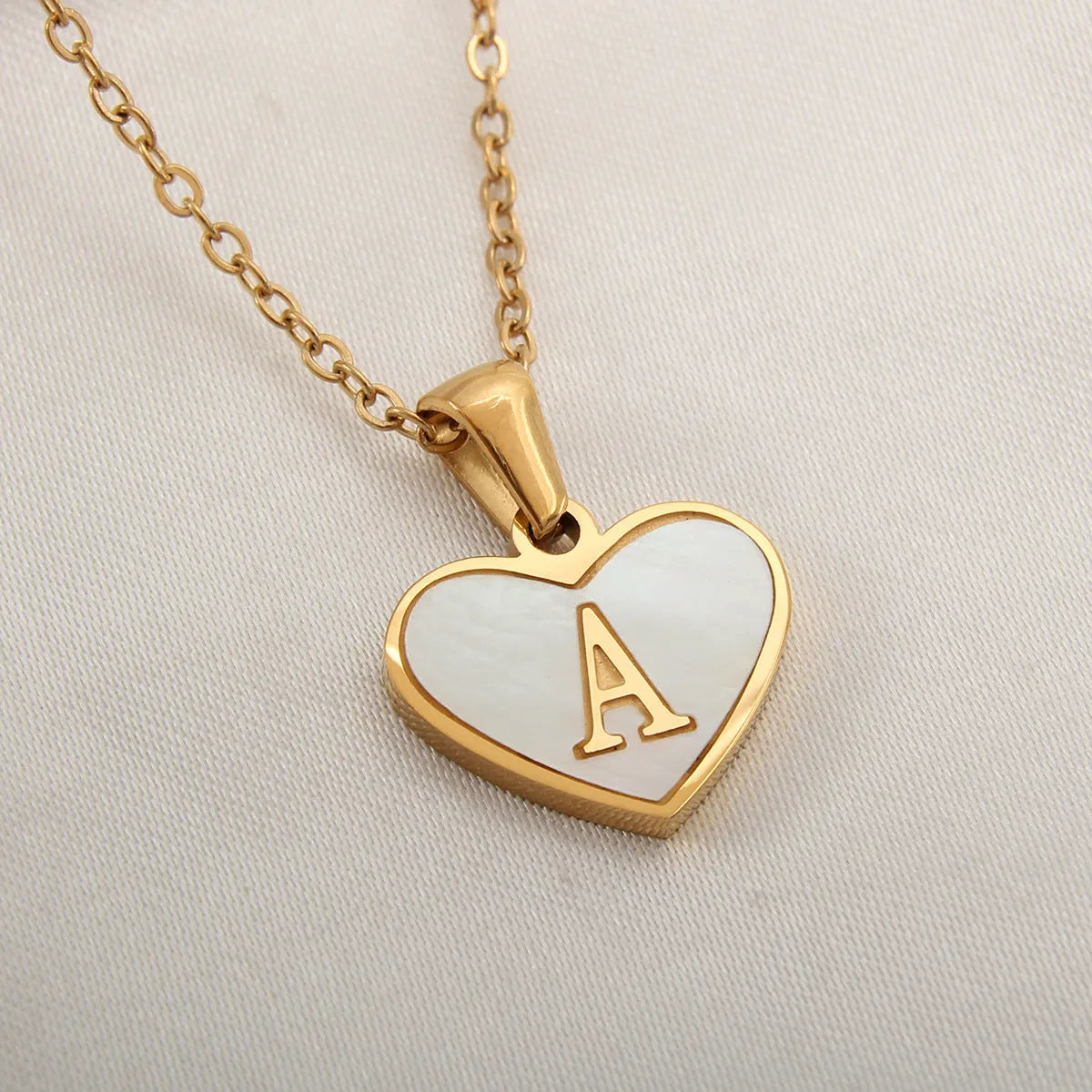 Gold plated heart-shaped white shell pendant personalised initial necklace on a stainless steel chain.