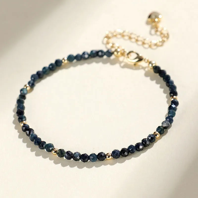 Close-up of a women's blue tourmaline gemstone beaded bracelet with 3mm beads and spacer design.