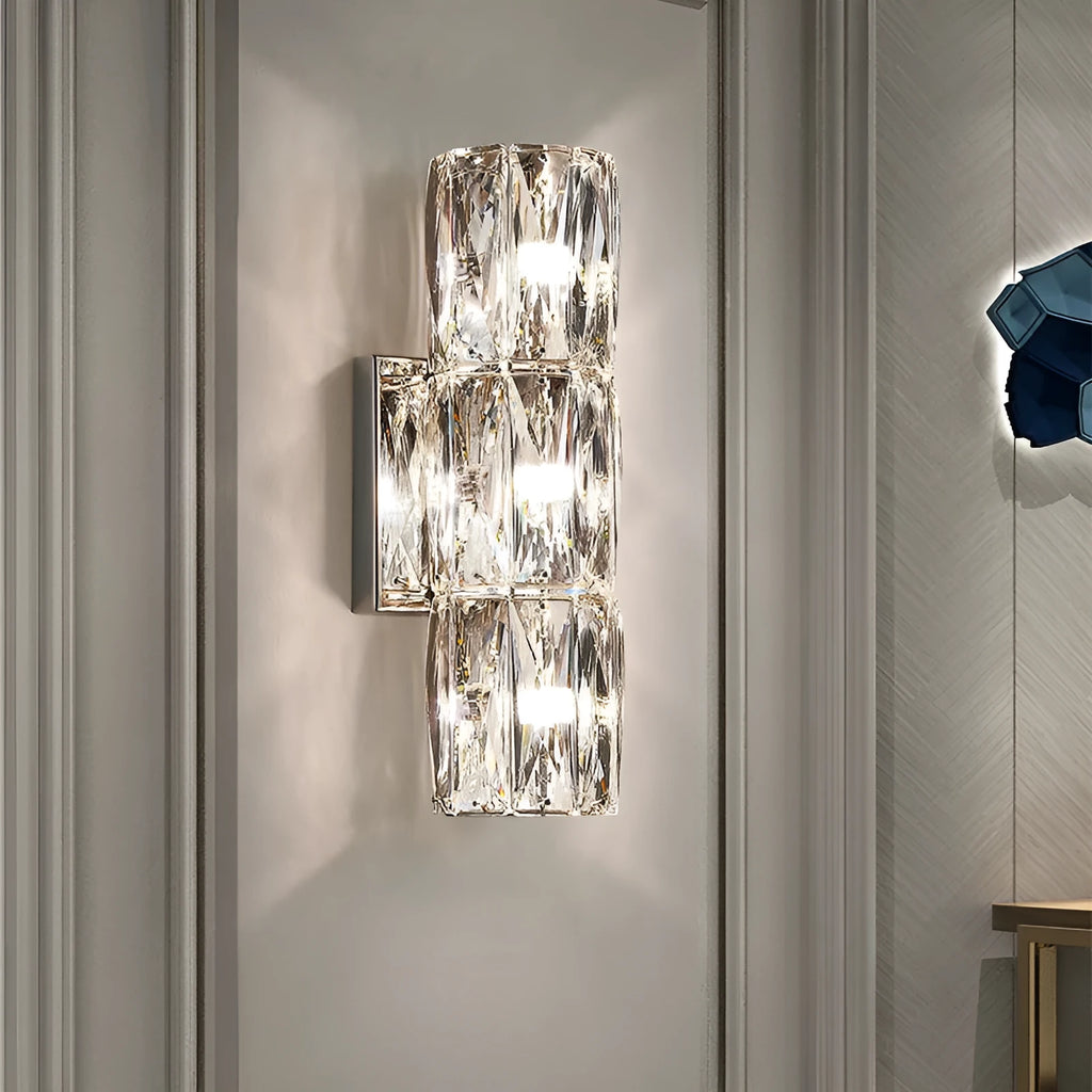 Slim crystal and stainless steel wall lamp with LED light on a wall.