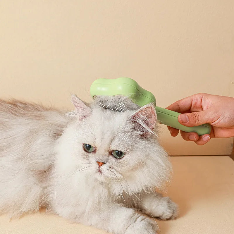 Green self-cleaning cat comb with stainless steel needle pins on a white background