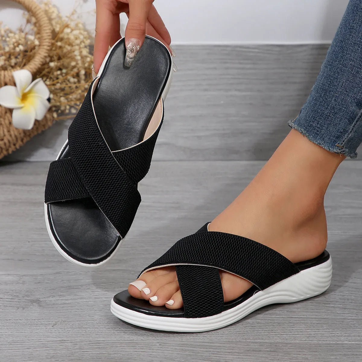 Women's black wedge slippers with a cross strap and peep toe on a thick rubber sole.