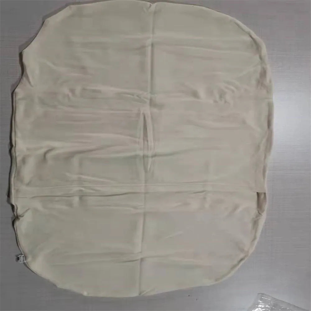 Beige portable baby nest crib cot for newborn infant on a bed